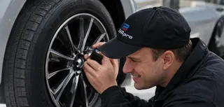 Специалист DVA.PRO с фонарём осматривает колесо, тормоза и подвеску